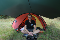 hacker with laptop in front of tent